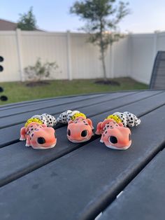 three toy animals sitting on top of a wooden table next to a white fence in the background