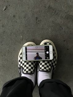 a person wearing black and white checkered shoes with their cell phone in front of them