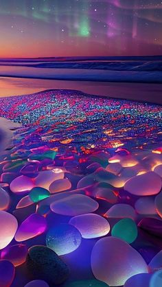 the sky is filled with many different colored lights and pebbles on the beach at night