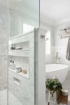 a bath room with a stand up shower and a tub next to a window on the wall