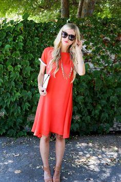 a woman wearing an orange dress and sunglasses