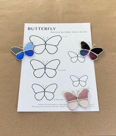 three butterfly shaped brooches sitting on top of a piece of paper next to each other