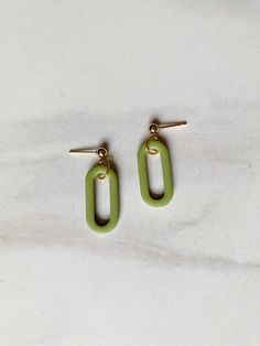 two pairs of green earrings sitting on top of a white surface