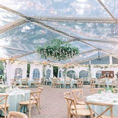 the inside of a tent with tables and chairs set up for an outdoor wedding reception