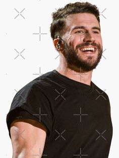 a man with ear buds on his ears smiles at the camera while wearing a black t - shirt