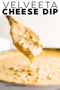 a spoon full of cheesy cheese dip is being lifted from a skillet