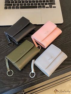 four wallets sitting on top of a table next to a laptop and keychain