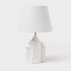 a white table lamp with a small house on it