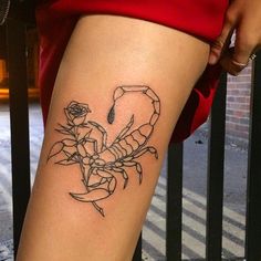 a woman's leg with a scorpion tattoo on her left thigh, and a rose in the center