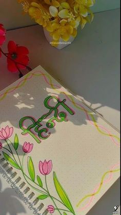 an open notebook sitting on top of a table next to flowers