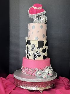 a three tiered cake with pink, black and white designs on it's sides