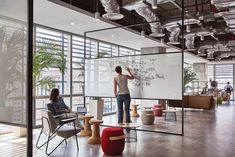 two people are standing in an office with glass walls and plants on the wall behind them