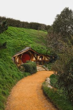 a dirt path leading to a hobbot house with grass on the roof and door