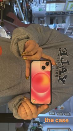 a person holding up a cell phone in front of their face and wearing a hoodie