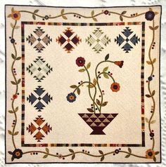 a quilted wall hanging with flowers in a vase on the front and back of it