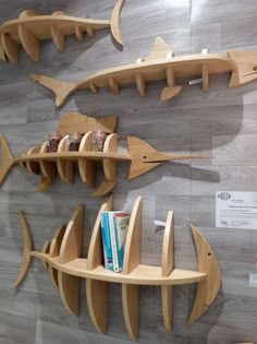 three wooden shelves with books on them and two fish shaped shelfs attached to the wall