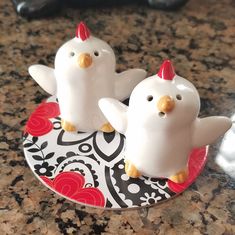 two little white birds sitting on top of a plate