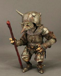 a figurine is holding a red stick and wearing an armor with horns on it