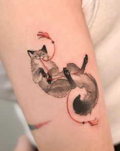 a woman's arm with a watercolor tattoo of two cats on the side