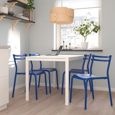 a white table with blue chairs and a laptop computer on it in a small room