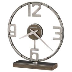 a clock with numbers on the face is shown in stainless steel and has a wooden base