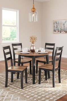 a dinning room table with four chairs and a vase on top of the table