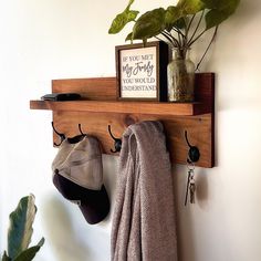 a wooden shelf with hats, hat hooks and a potted plant hanging on it