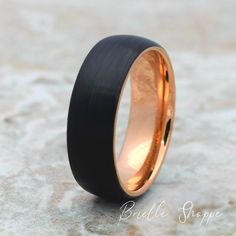 a black and gold wedding ring on top of a rock