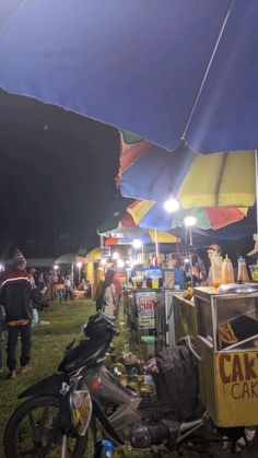 a motorcycle parked next to a tent with food on it and people standing in the background