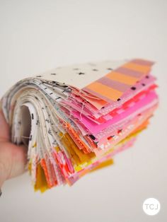 a hand holding a stack of different colored papers