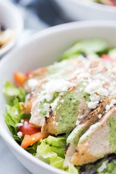 a salad with chicken, lettuce and tomatoes in a bowl on the table