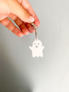 a hand holding a keychain with a ghost on it