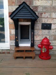 a red fire hydrant sitting in front of a brick wall next to a small dog house