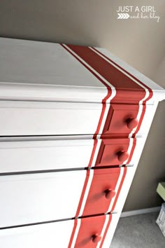 a white dresser with red trim and drawers on the bottom is featured in this post