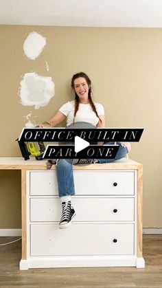 a woman sitting on top of a white dresser next to a sign that says office bulletin fair one