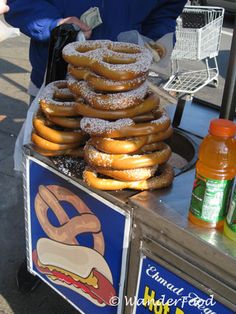 donuts are stacked on top of each other in front of a food cart at an outdoor market