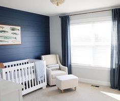 a baby's room with blue walls, white furniture and a crib in the corner