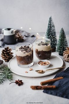 two desserts are sitting on a plate with pine cones and cinnamon sticks around them