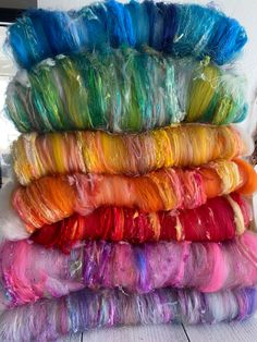 several skeins of yarn are stacked on top of each other in different colors