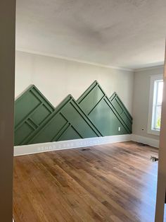 an empty room with wood floors and green wall panels