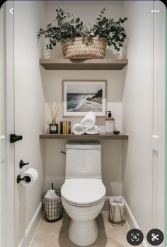 a white toilet sitting in a bathroom next to a shelf filled with towels and plants