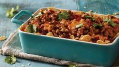 a casserole dish with meat and vegetables in it sitting on a blue cloth