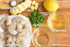 shrimp, butter and parsley on a wooden table next to wine glasses with lemons