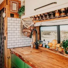 a kitchen area with wooden counter tops and white tiled walls, along with potted plants on the window sill