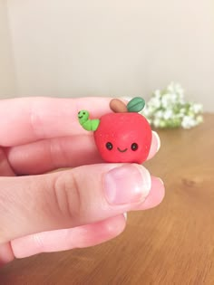 a hand holding an apple with two green leaves on it