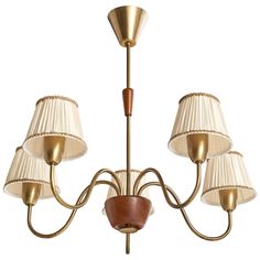 a chandelier with five shades of white and gold on the lampshades