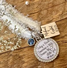 a personalized necklace with two charms and a name tag attached to it on a piece of wood