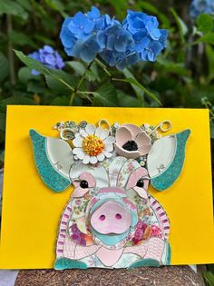 a close up of a card with a cow on it and flowers in the background