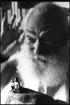 an old man with long white hair and beard holding a small figurine in his hand