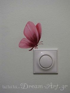 a pink flower sitting on top of a white light switch